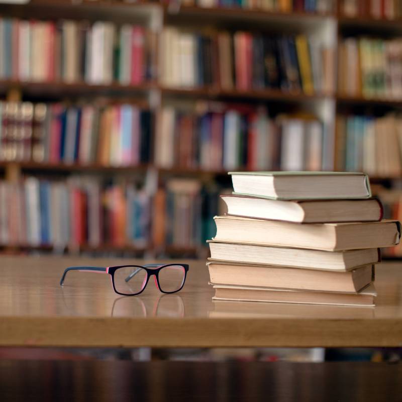 Stack of books in a library with glasses on top